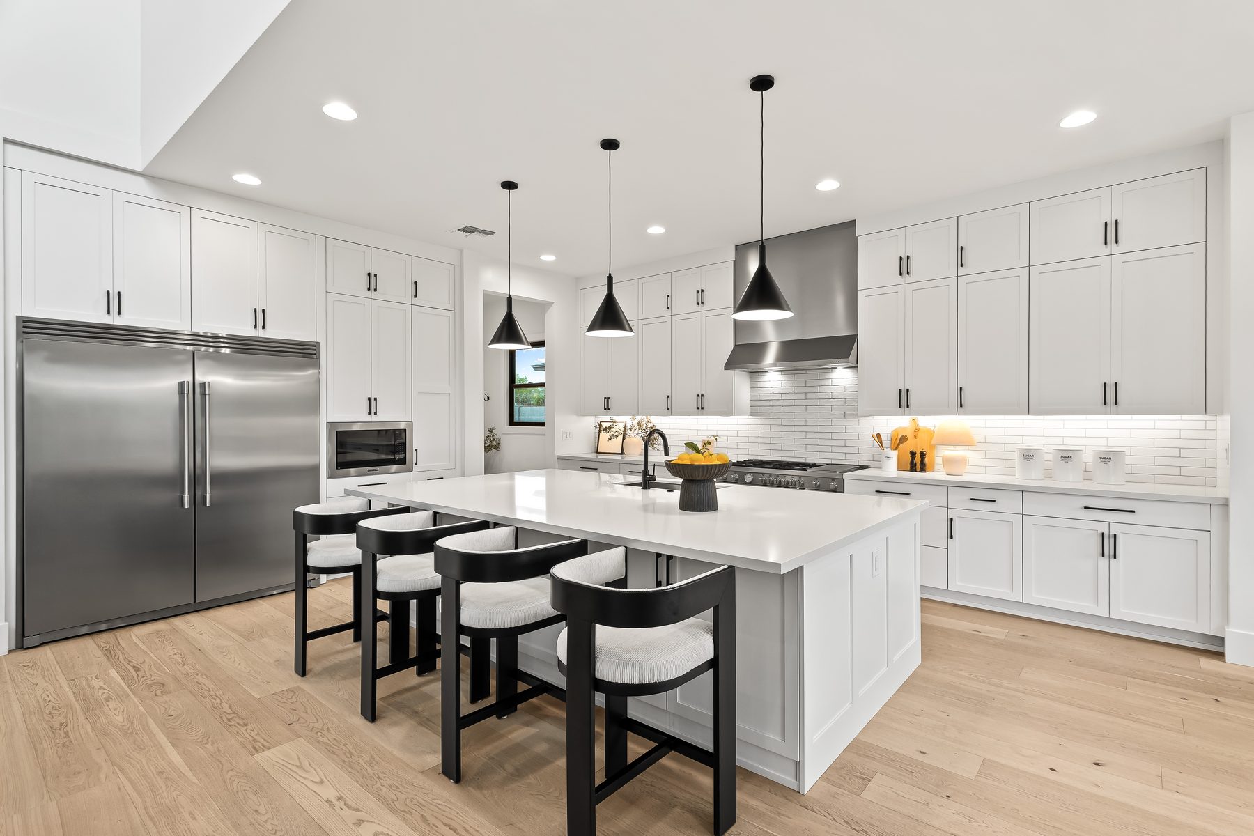 Chef's kitchen with quartz island, black pendant lights, and built-in refrigerator in Arcadia, Phoenix